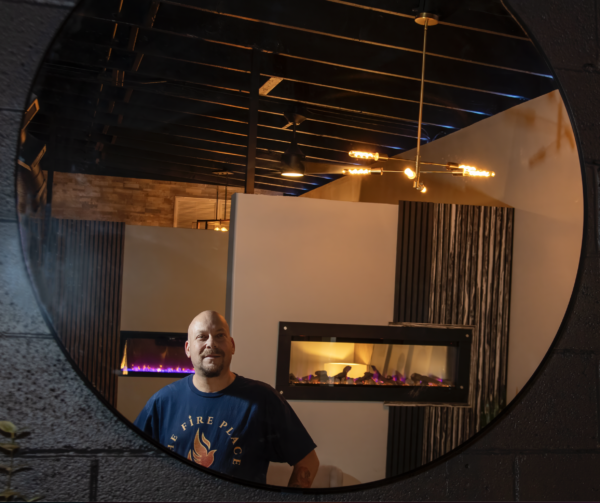 Photo of a man standing in front of several fireplaces - photo taken through a mirror