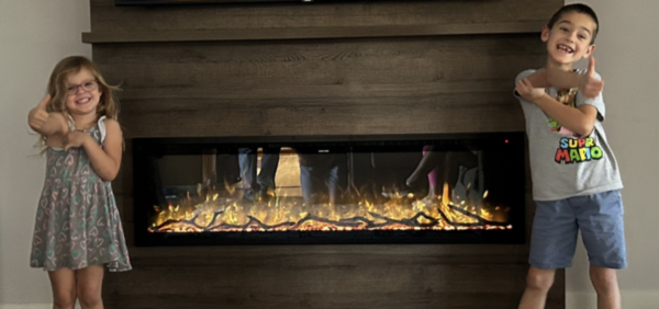 electric fireplace in walnut wood media wall with two children giving the thumbs up sign